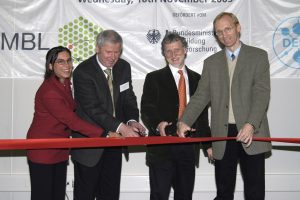 Four people smile for camera during a ribbon cutting ceremony