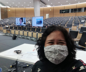 Conference Officer Diah wearing a face mask in an empty auditorium during a virtual event
