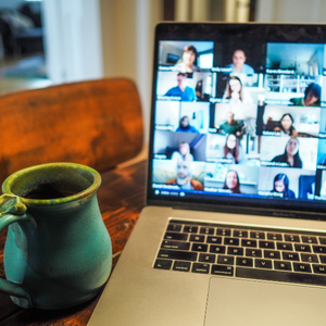 desk with mug and laptop with a virtual meeting live on screen