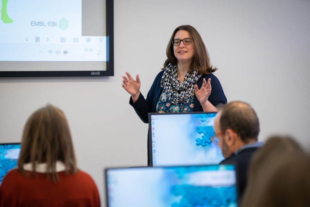 Anna Swan, one of the EMBL-EBI Trainers, is presenting from the front of the EMBL-EBI Training Suite