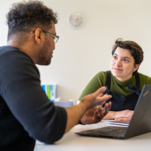 two workers discuss over a laptop