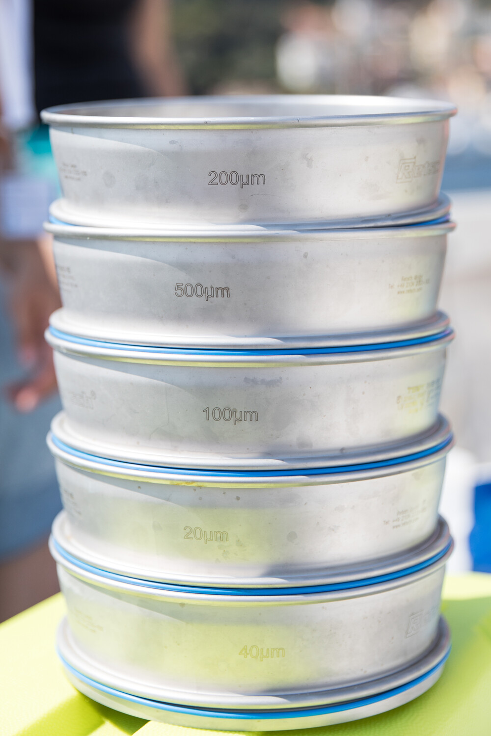 The collected water/plankton sample is then filtered on the boat. Depending on how big the organisms are that the scientists are interested in, different sized sieves are used to break down the bigger water sample into several small samples that contain the organisms of interest. This process is also called “fractionation”. Die gesammelte Wasser-/Planktonprobe wird anschließend auf dem Boot gefiltert. Je nachdem, wie groß die Organismen sind, an denen die WissenschaftlerInnen interessiert sind, werden unterschiedlich große Siebe verwendet, um die größere Wasserprobe in mehrere kleine Proben zu zerlegen, die die jeweiligen Organismen von Interesse enthalten. Dieser Prozess wird auch als “Fraktionierung” bezeichnet.