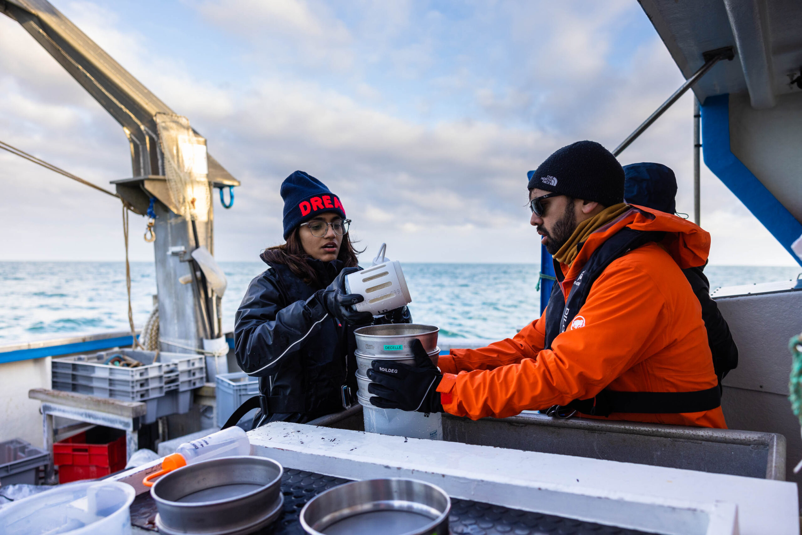 The collected water/plankton sample is then filtered on the boat. Depending on how big the organisms are that the scientists are interested in, different sized sieves are used to break down the bigger water sample into several small samples that contain the organisms of interest. This process is also called “fractionation”. Die gesammelte Wasser-/Planktonprobe wird anschließend auf dem Boot gefiltert. Je nachdem, wie groß die Organismen sind, an denen die WissenschaftlerInnen interessiert sind, werden unterschiedlich große Siebe verwendet, um die größere Wasserprobe in mehrere kleine Proben zu zerlegen, die die jeweiligen Organismen von Interesse enthalten. Dieser Prozess wird auch als “Fraktionierung” bezeichnet.