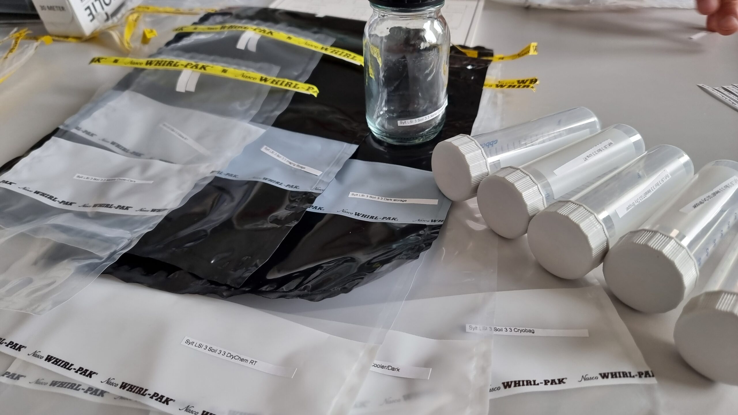 Before the scientists head out for the sampling site, the equipment is labeled and prepared. This helps the researchers to be able to tell later where a sample was taken and what it contains. For sediment sampling, consumables like tubes, glass vials and bags are prepared and labeled before sampling. Bevor sich die WissenschaftlerInnen auf den Weg zur Probenahmestelle machen, wird die Ausrüstung beschriftet und vorbereitet. So können die Forschenden später nachvollziehen, wo eine Probe entnommen wurde und was sie enthält. Für Sedimentproben werden Verbrauchsmaterialien wie Röhrchen, Glasfläschchen und Beutel vor der Probenahme vorbereitet und beschriftet.