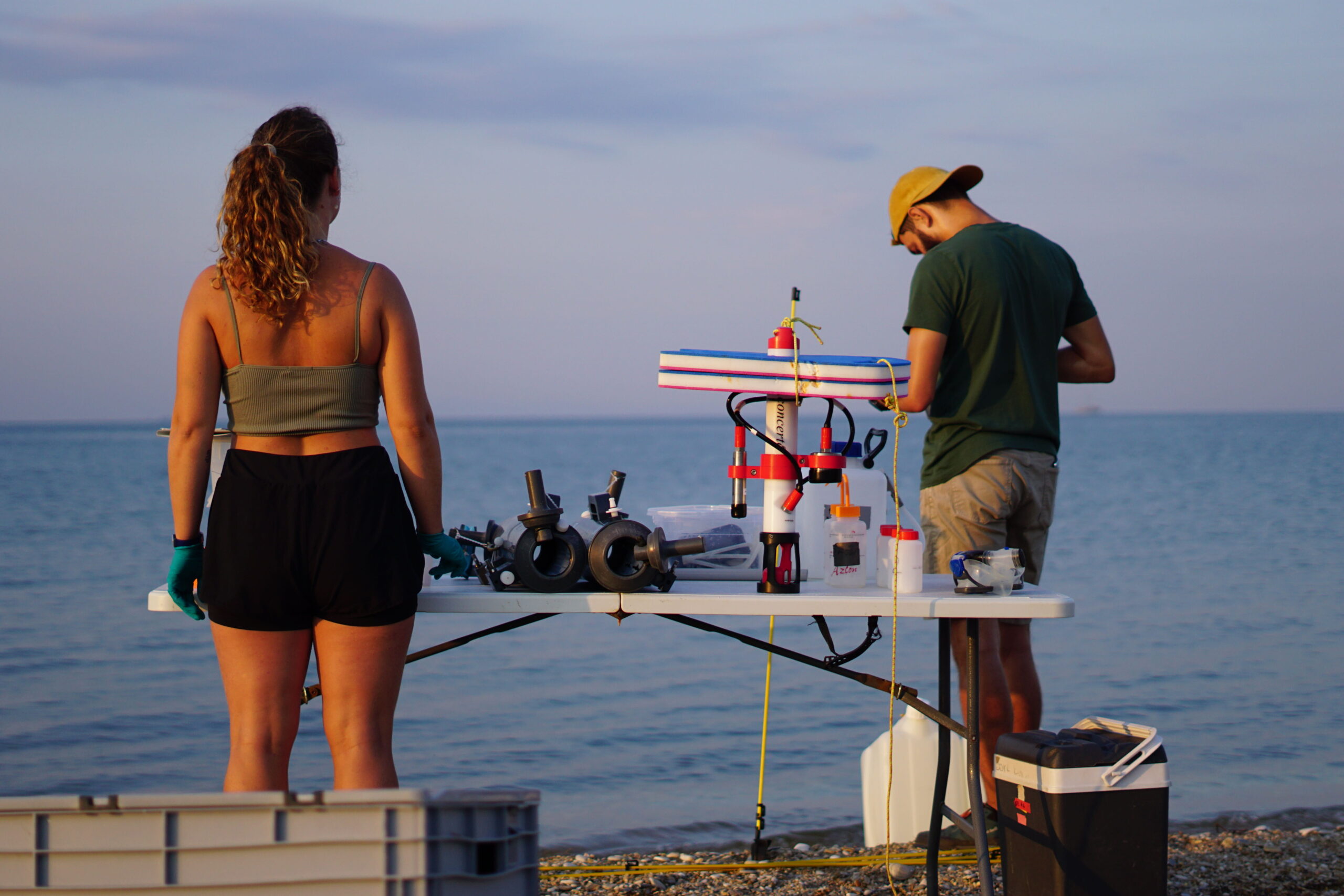 Before the scientists can start their sampling, all sampling equipment has to be prepared: For water sampling, needed equipment include so-called Niskin bottles for water collection, a CTD sensor for water conductivity (C), temperature (T) and depth (D) measurements and different collection vials and canisters. Bevor die WissenschaftlerInnen beginnen können, Proben zu nehmen, muss die Ausrüstung vorbereitet werden: Für Wasserproben werden sogenannte Niskin-Flaschen für die Wasserentnahme, ein CTD-Sensor für die Messung der Wasserleitfähigkeit (engl. conductivity (C)), -temperatur (T) und -tiefe (engl. depth (D)) sowei verschiedene Auffanggefäße und Kanister benötigt.