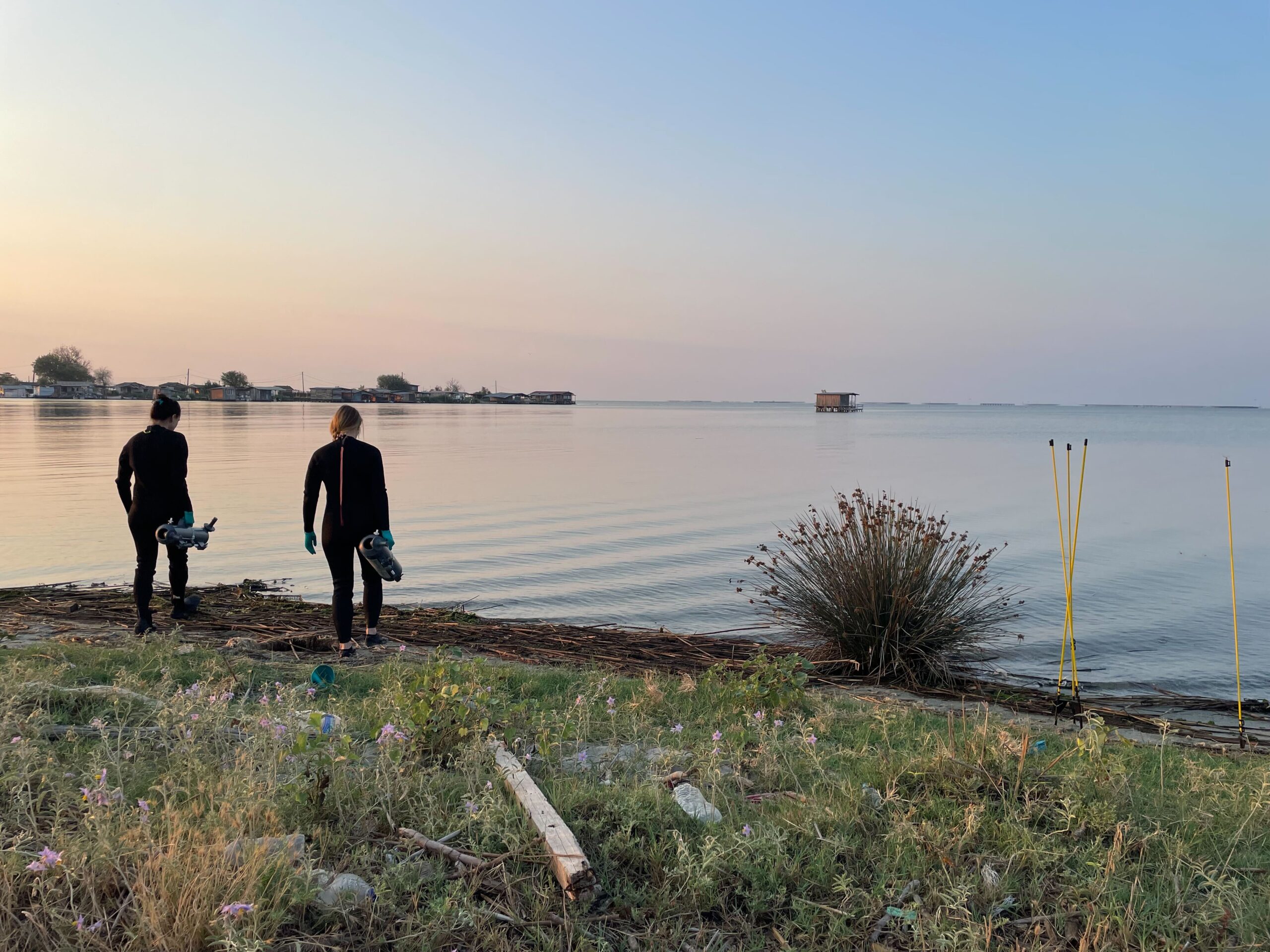 Then, the scientists make their way to the sampling site with the Niskin Bottles and take samples in waist-high water. Dann machen sich die WissenschaftlerInnen mit den Niskin-Flaschen auf den Weg zur Probenahmestelle und nehmen im hüfthohen Wasser Proben.