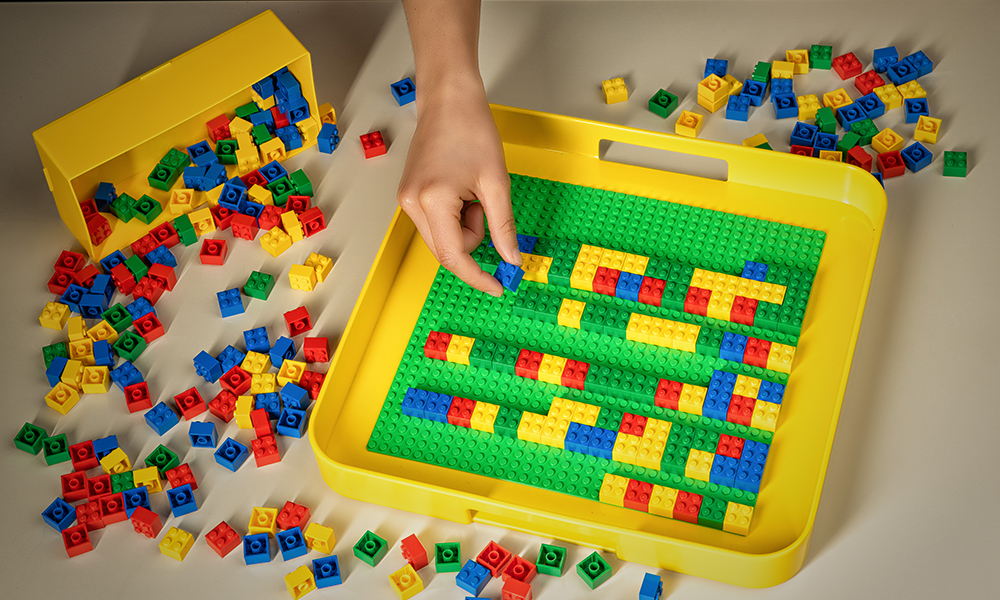 Hand playing with Lego bricks.