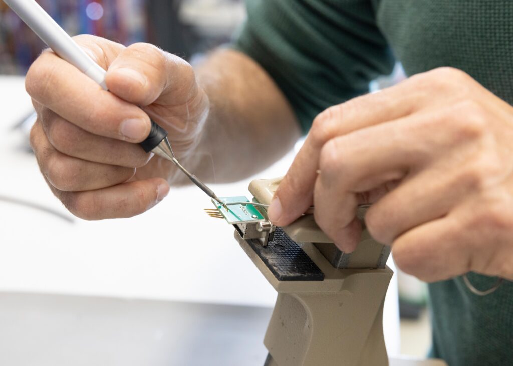 A technician soldering electrical connectors onto a printed circuit board