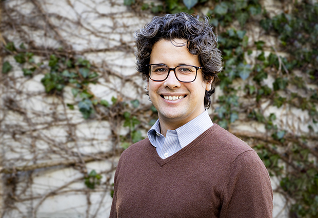 A smiling Santiago Rompani, new group leader at EMBL Rome, stands in front of a vine covered wall