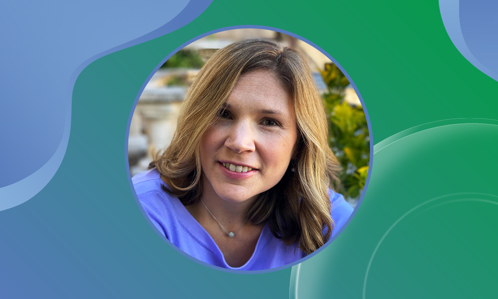 Portrait picture of Erin Tranfield, member of the EMBL Alumni Association Board, against a blue-green background.