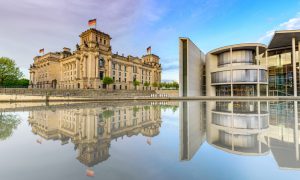 The Reichstag building (left) and Paul-Löbe-Haus (right) in Berlin, as seen in daylight from across the Spree river.