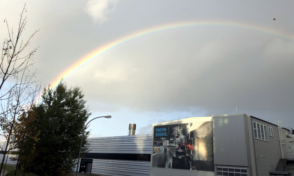 Rainbow on a cloudy sky above technical buildings.