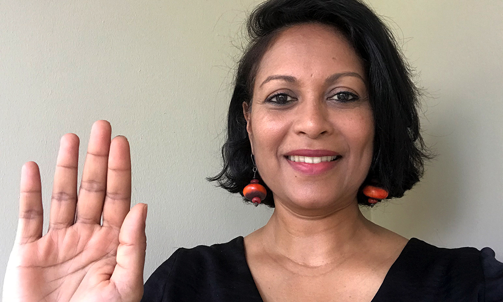 Roshni Mooneeram, EMBL's Equality and Diversity Officer, strikes the #ChooseToChallenge pose with her hand high, pledging to call out bias, and actively question stereotypes.