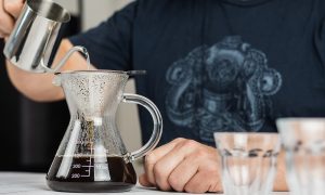 Man pouring water in a glass bottle to make coffee.