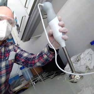 EMBL researcher Stefano Da Vela holds an immersion blender over a glass beaker containing plastic pieces.