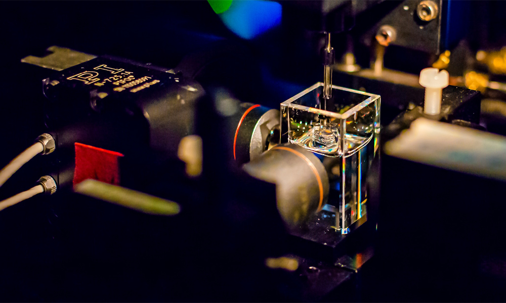 Close up of the interior of a light-sheet microscope, featuring optical equipment and a transparent cube.