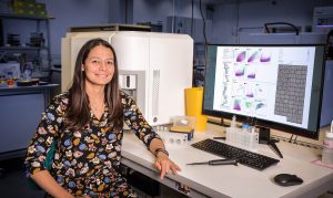 Female scientist sits in front of computer showing the results of flow cytometry experiment.