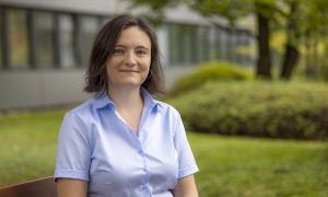 female scientist sits in front of building