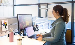 woman stands in front of computer in workplace