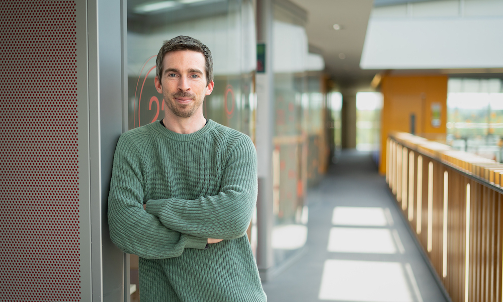 Man leaning against a window with corridor in the background