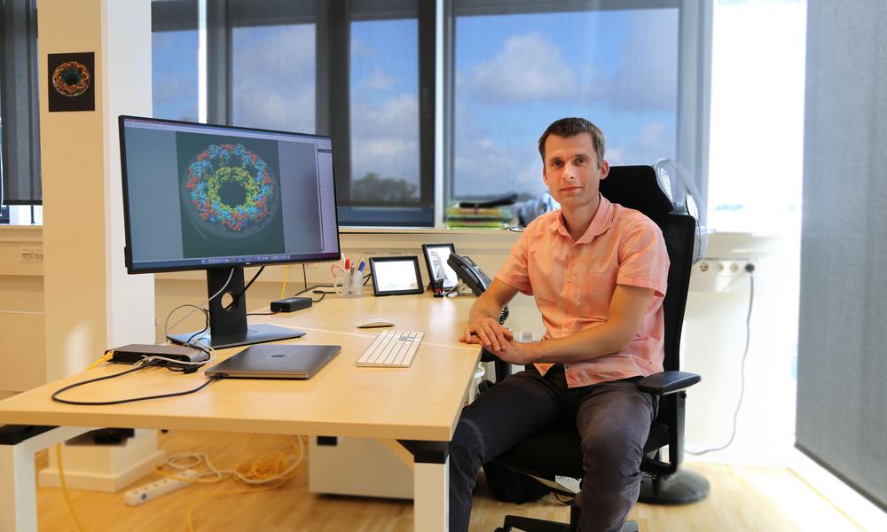 Jan Kosiński in his office in the Centre for Structural Systems Biology Hamburg. The computer screen is displaying the model of the structure of the nuclear pore complex.
