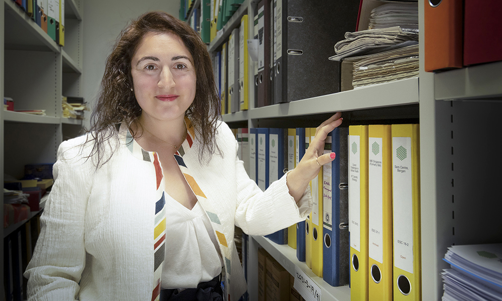 A woman stands in front of shelving filled with notebook binders.