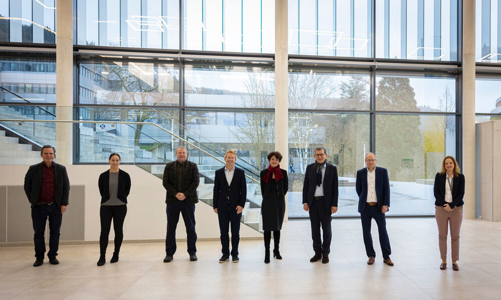 8 representatives of both the Dieter Schwarz Foundation and EMBL are standing in the EMBL Imaging Centre foyer facing the camera
