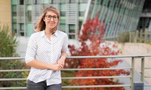 Woman wearing white top leaning against metal handrail