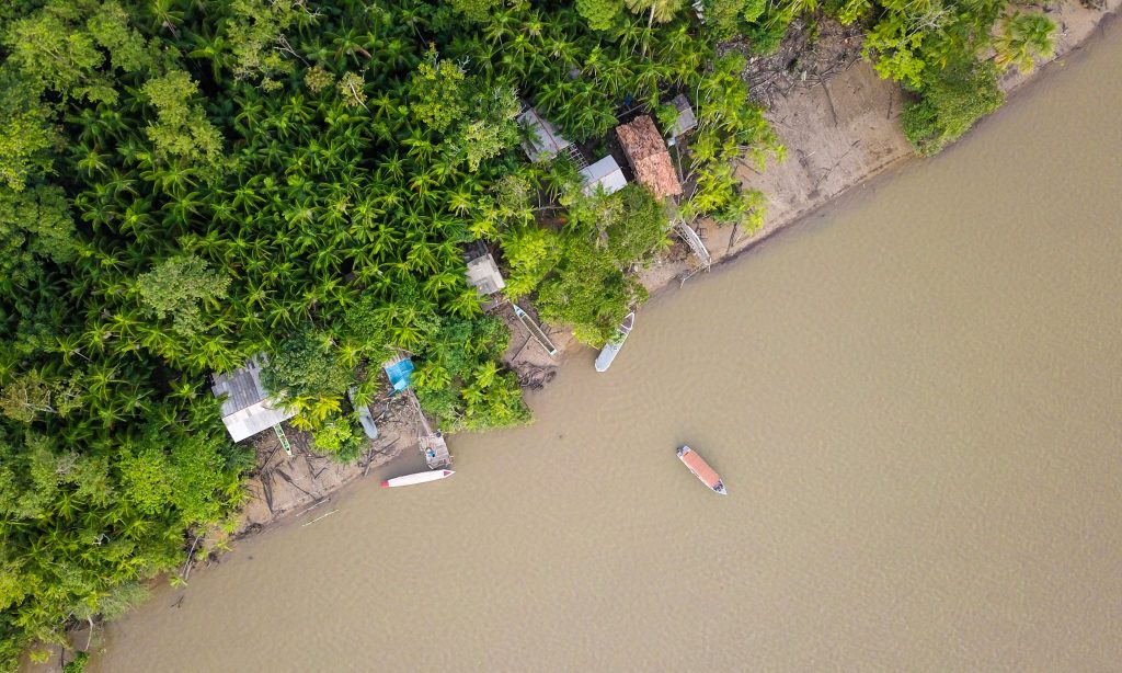 Aerial view of a riverbank with trees and boats visible.
