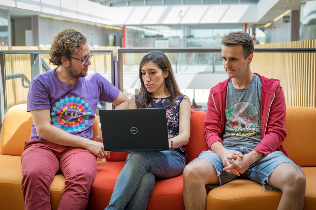 Three workshop participants seated on a sofa and looking at a computer screen.