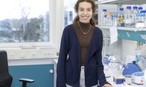 Female student stands in front of a lab bench