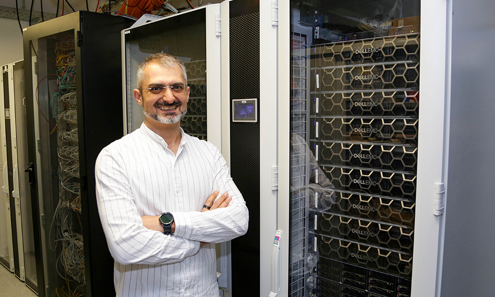 Photo of Eduard Avetisyan smiling and standing next to the servers at EMBL Hamburg.