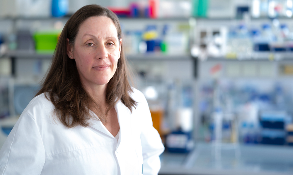 Photo of Audrey Spielmann, white woman with long brown hair wearing a lab coat