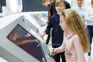 young girl stands in front of video monitor