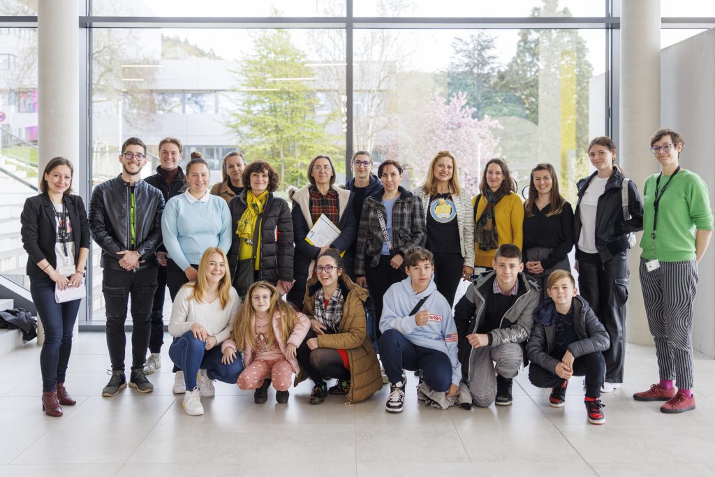 two rows of scientists and students in front of large window