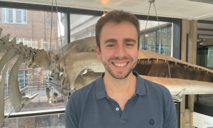 Picture of a man standing in front of a dinosaur skeleton.