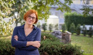 White woman with short red hair standing in garden in front of a tree. Picture of Angelika Thomasson. Credits: Marcos Lopez-Marrero/EMBL
