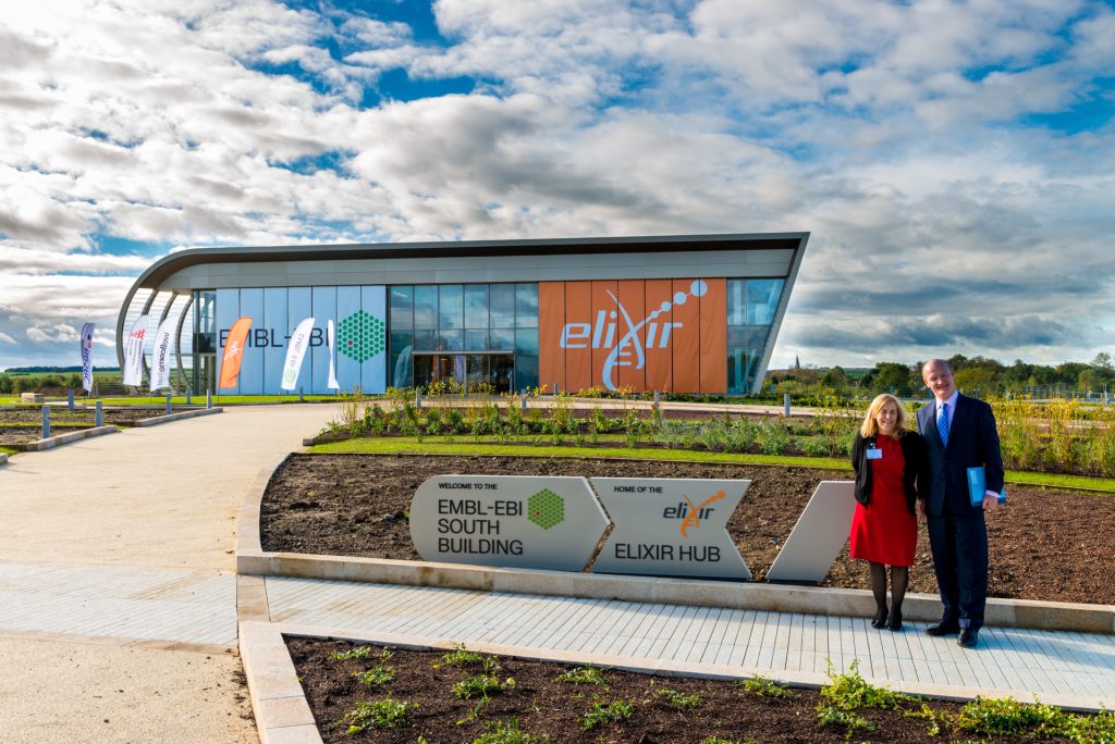 Two people (male and female) standing in front of a building.