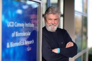 Male scientist in front of a sign.