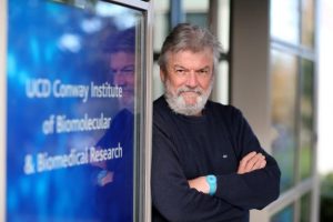 Male scientist in front of a sign.