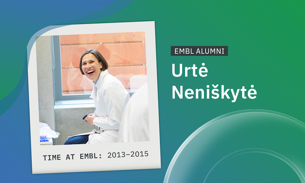 Female scientist in white lab coat enjoying camaraderie of colleagues.