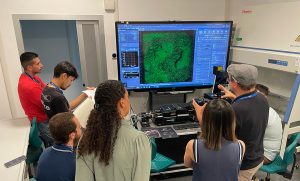 Participants listen to the trainer in front of a screen displaying a microscopy image