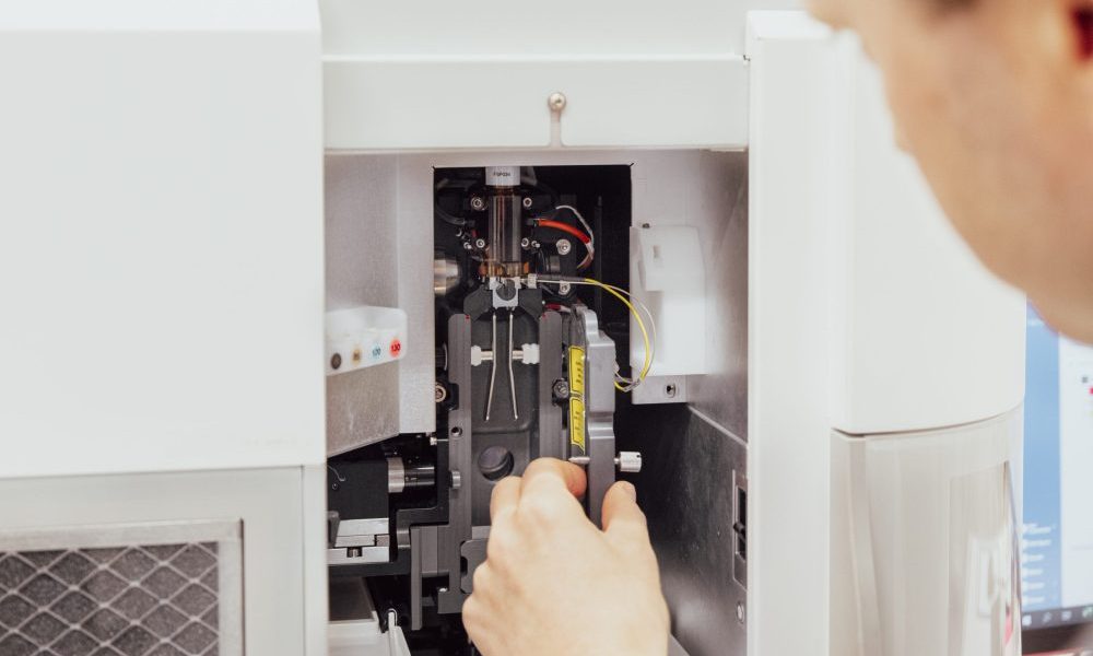 A close-up of the flow chamber of an ICS machine, with a scientist’s hand in the foreground.