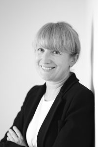 Female scientist looks directly at the camera with her arms folded. 