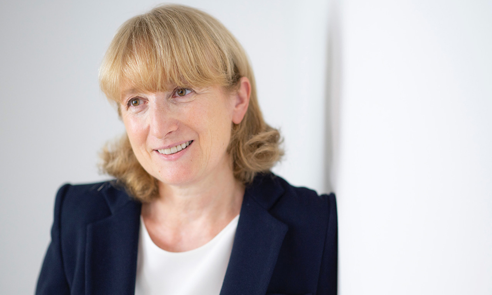 Female scientist looks directly at the camera, wearing blue jacket and white top