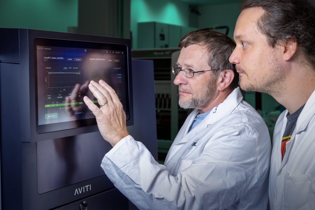 Two male scientists in lab coats looking at.a computer screen