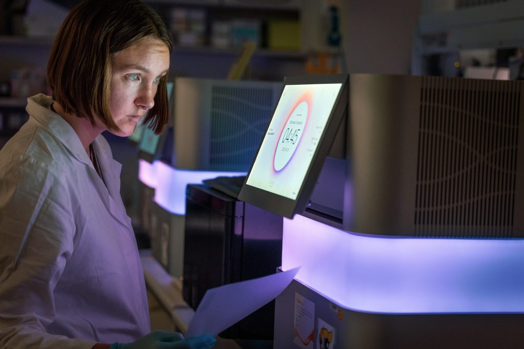 A female researcher looking at an illumina sequencer. 