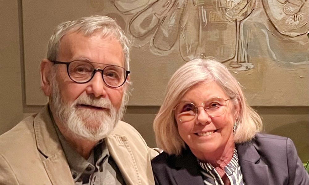 A man and a woman looking at the camera, parts of a restaurant are visible in the background.