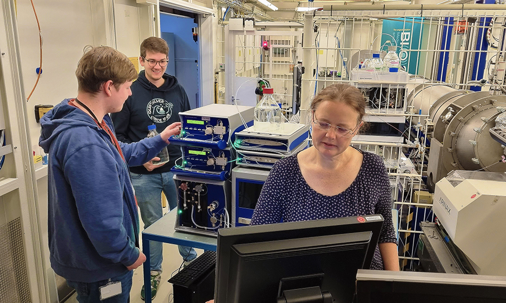 Three scientists are working in a room full of experimental equipment for X-ray experiments.