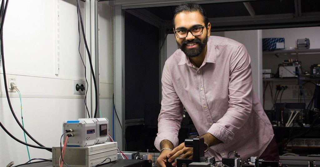 Male scientist looks at camera while working with instrumentation.